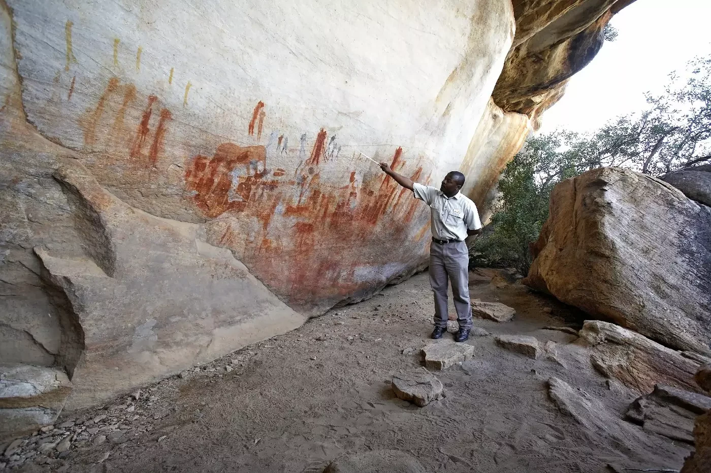 Guide explaining San rock paintings in a sandstone shelter at Bushmans Kloof