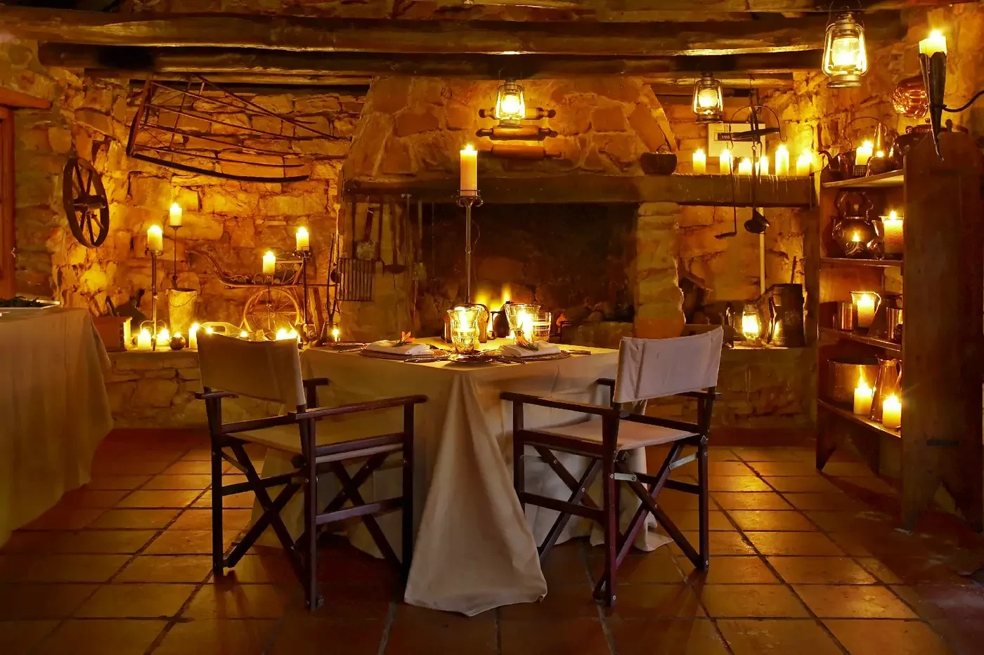 Candlelit table beneath timber rafters in the stone-walled Kadoro cottage at Bushmans Kloof