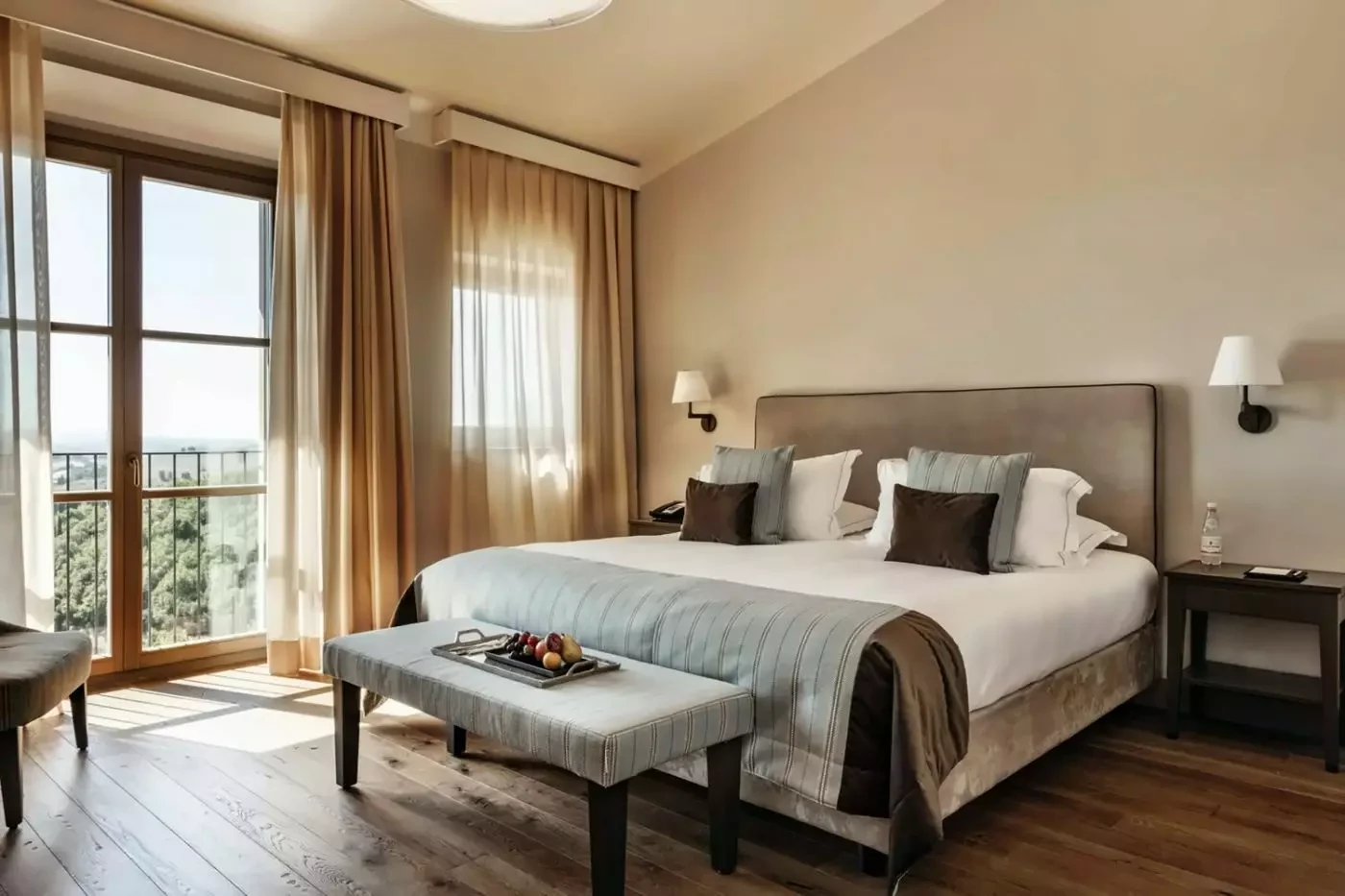 Bedroom at Castelfalfi with a bench at the foot of the bed and tall windows