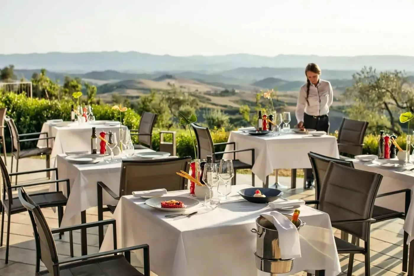 Tables set for a meal on a terrace overlooking the Castelfalfi countryside