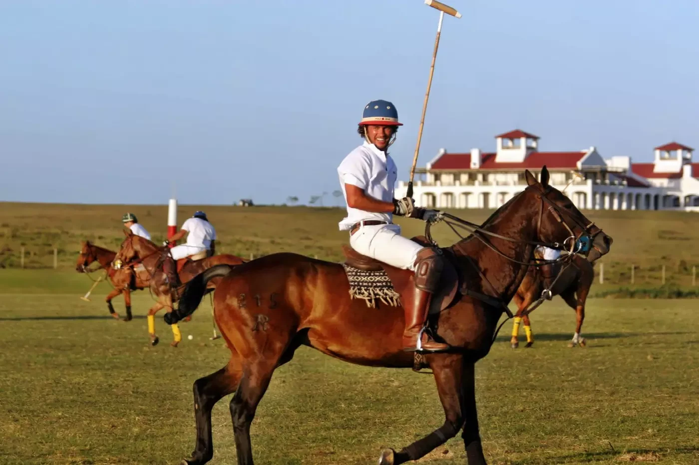 Polo riders on horseback with Estancia Vik in the background