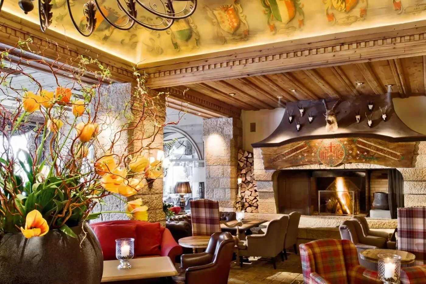 Timber-ceilinged lounge with a fireplace and floral arrangements at Gstaad Palace
