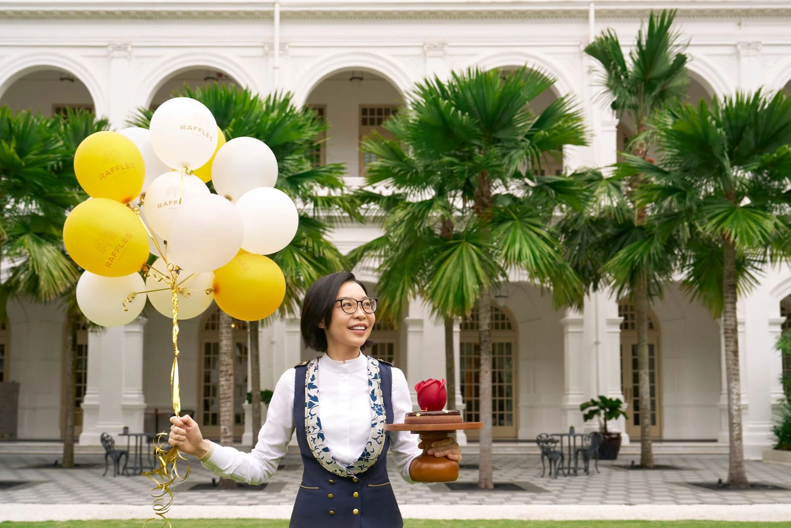 Raffles Singapore butler carrying balloons and a gift in the hotel courtyard