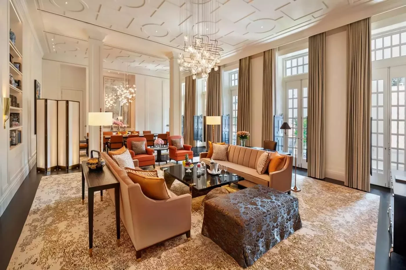 Suite sitting room at Raffles Singapore with orange sofas and tall windows