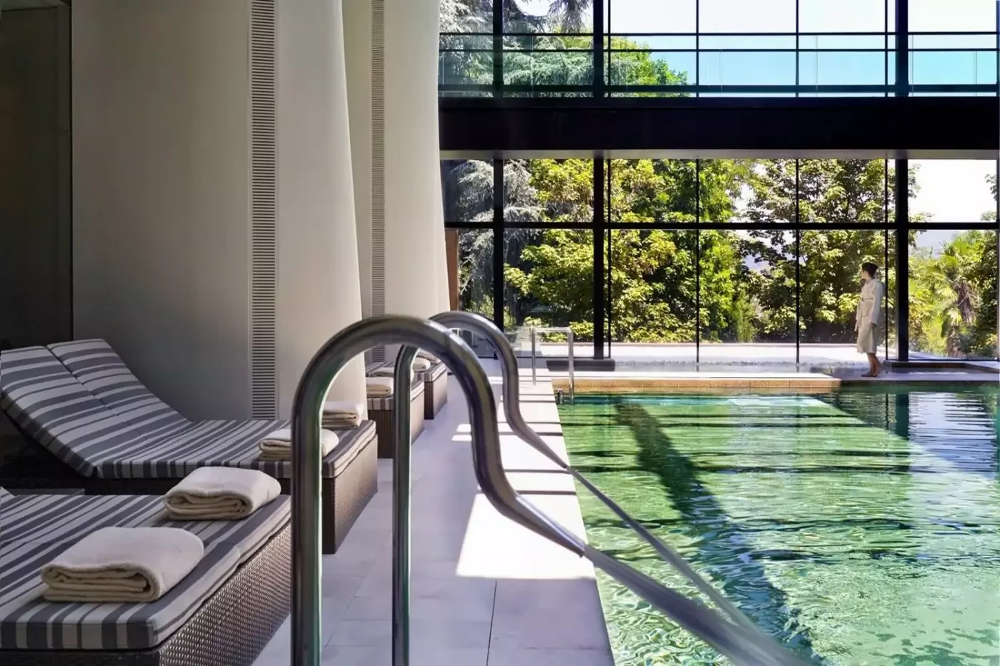 Indoor pool and loungers beside garden-facing windows at Six Senses Douro Valley
