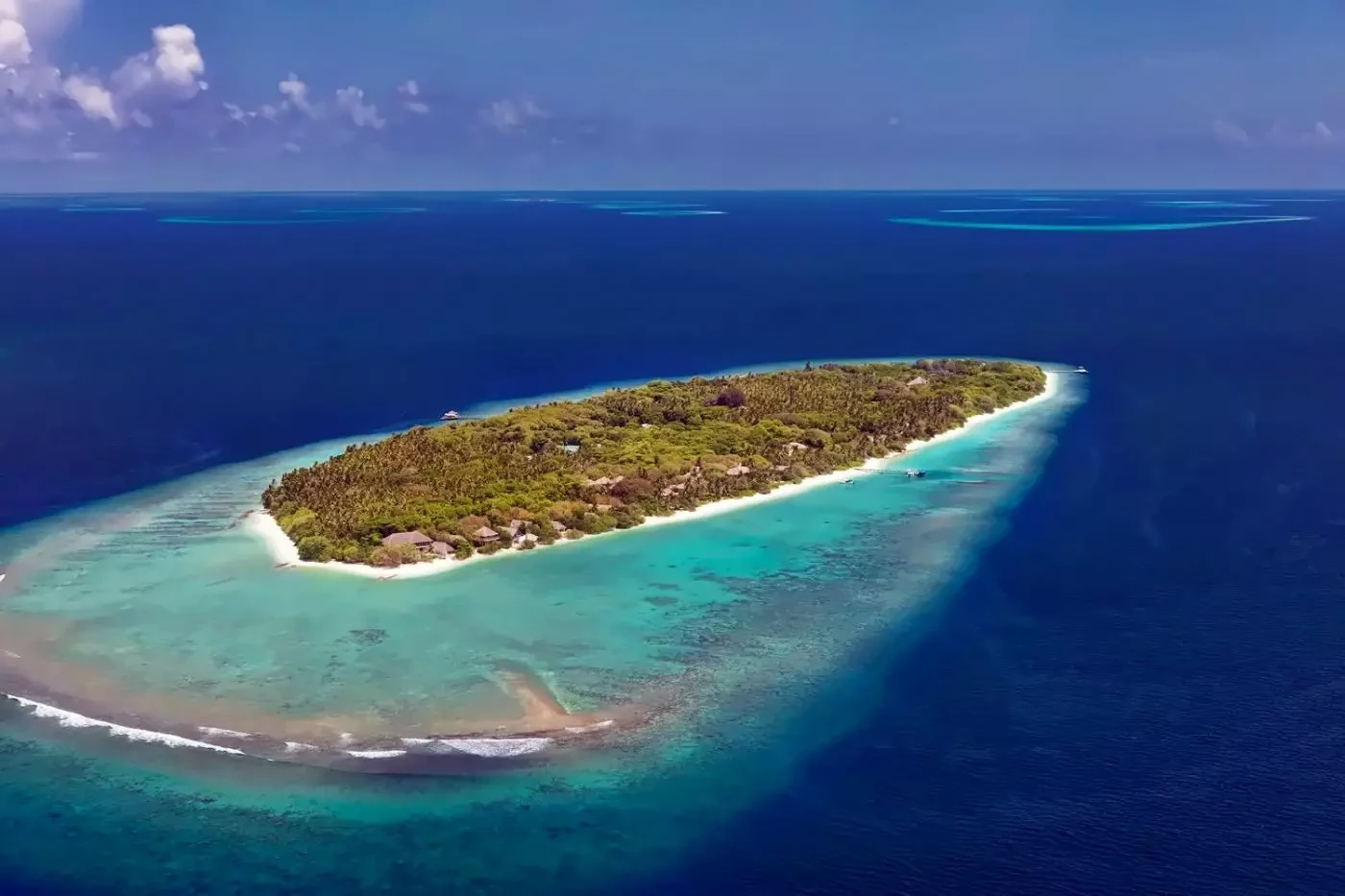 Aerial view of Soneva Fushi surrounded by reef and deep blue water in Baa Atoll