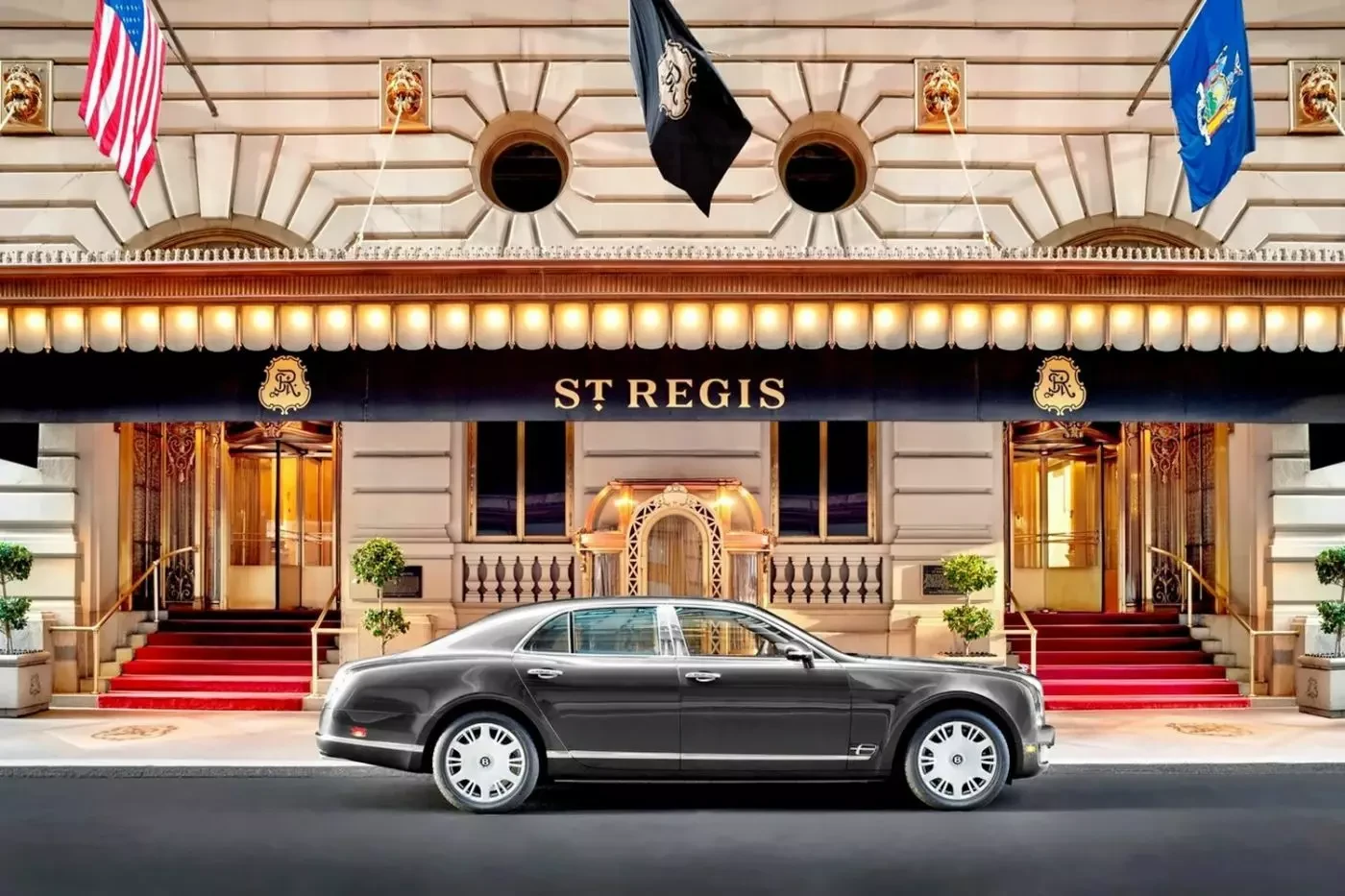 Canopied entrance of The St. Regis New York with red-carpeted steps and flags