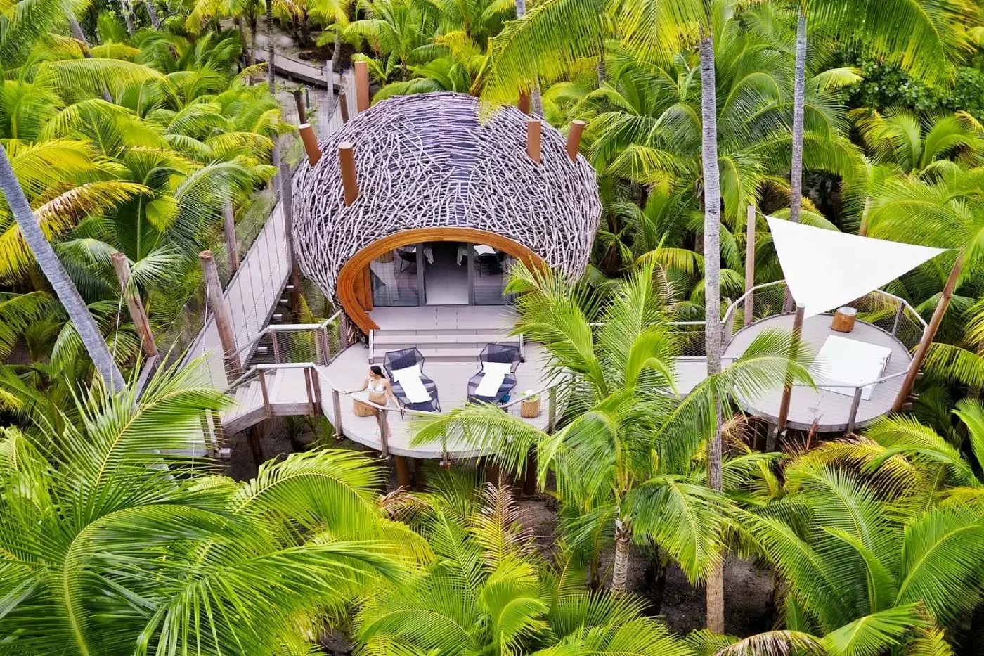 Elevated woven spa pavilion surrounded by tropical greenery at The Brando