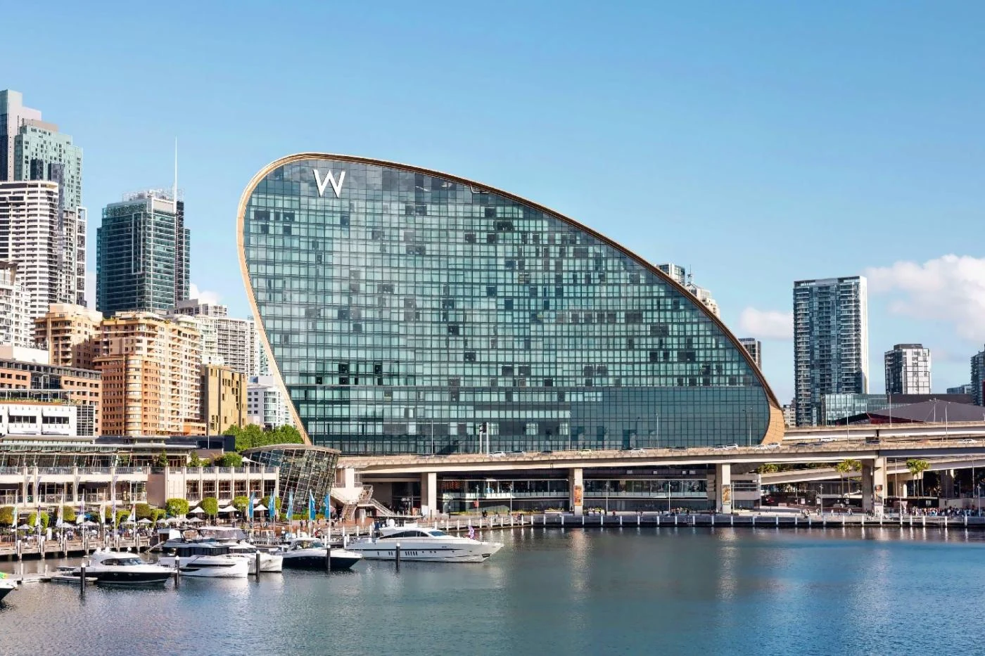 W Sydney's curved glass building overlooking boats in Darling Harbour